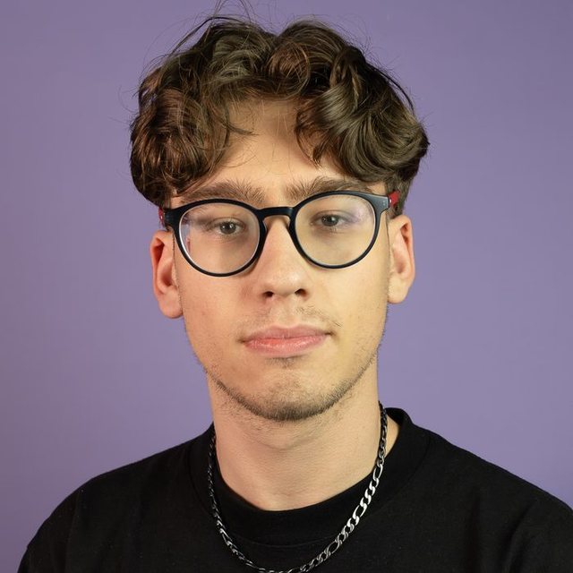 Portrait de Baptiste Linden, fondateur de BAI Agency, souriant légèrement, lunettes rondes, sur fond violet